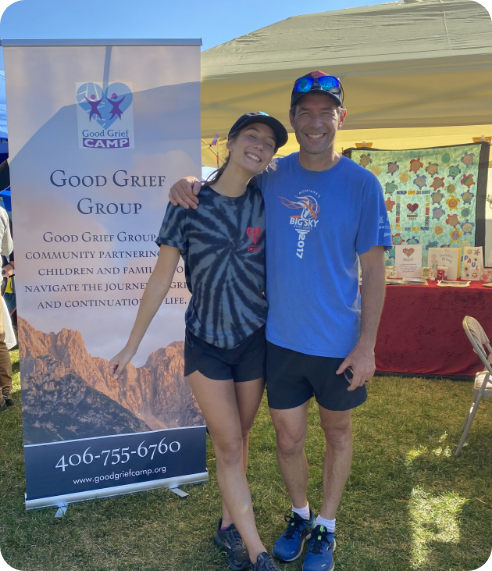 Good Grief volunteers posing in front of an event banner and tent